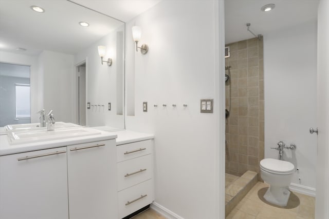 bathroom with vanity, toilet, tile patterned flooring, and a tile shower