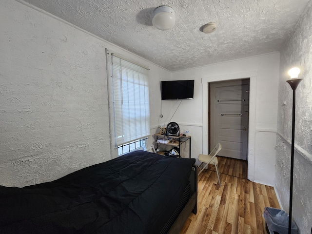 bedroom with a textured ceiling and hardwood / wood-style flooring