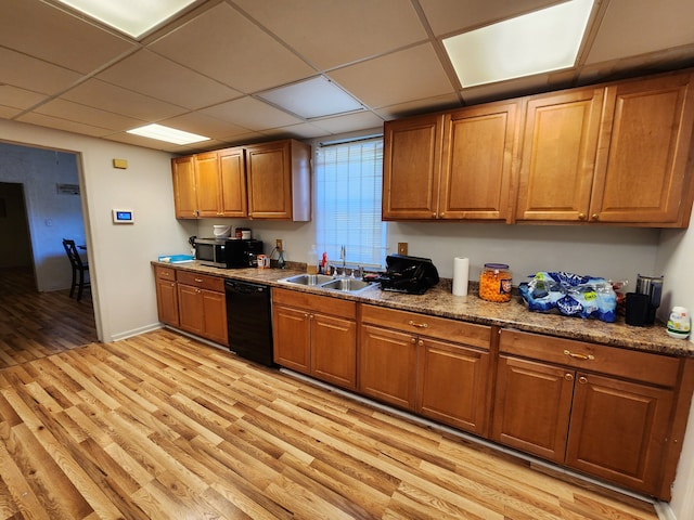 kitchen featuring a drop ceiling, sink, light hardwood / wood-style floors, and black dishwasher