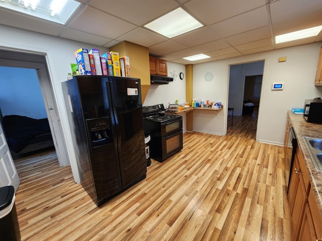 kitchen featuring a paneled ceiling, light hardwood / wood-style flooring, extractor fan, and black appliances