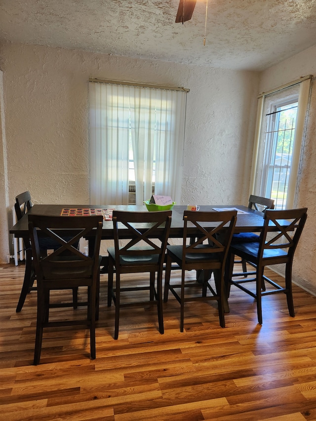 dining area featuring wood-type flooring and a textured ceiling