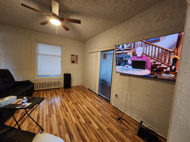 living room featuring hardwood / wood-style floors, lofted ceiling, ceiling fan, a textured ceiling, and radiator heating unit