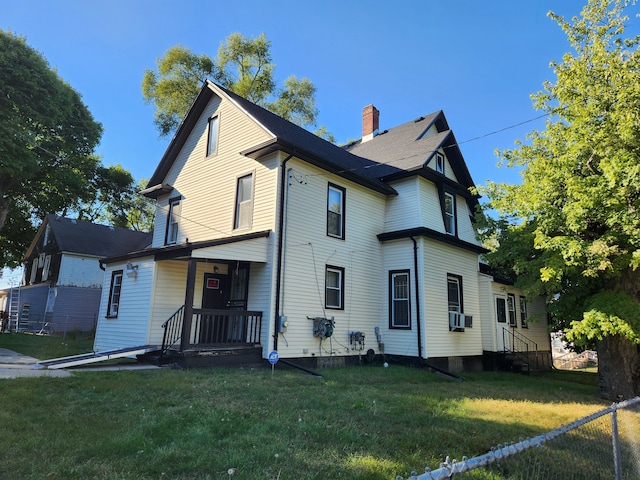 rear view of property featuring a lawn and cooling unit