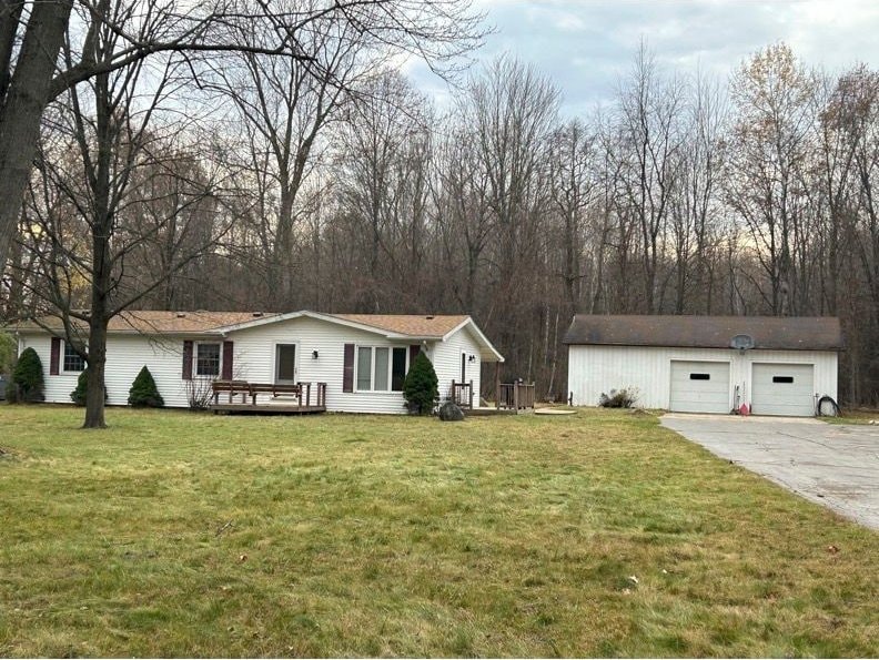 view of front of property with a front yard, a garage, an outdoor structure, and a wooden deck