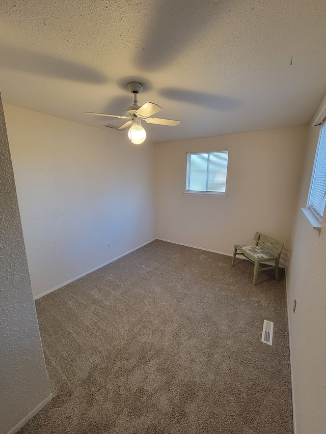 carpeted spare room with ceiling fan and a textured ceiling