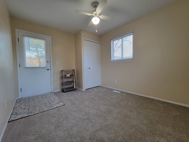 interior space featuring light carpet and ceiling fan