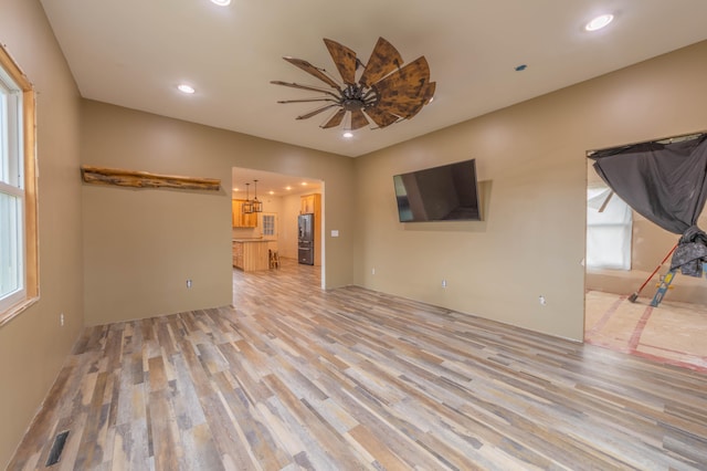 unfurnished living room featuring ceiling fan and light hardwood / wood-style flooring