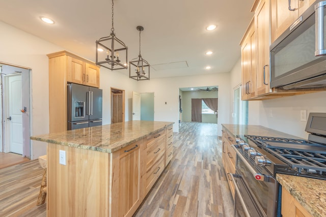 kitchen with appliances with stainless steel finishes, light wood-type flooring, light brown cabinetry, and pendant lighting