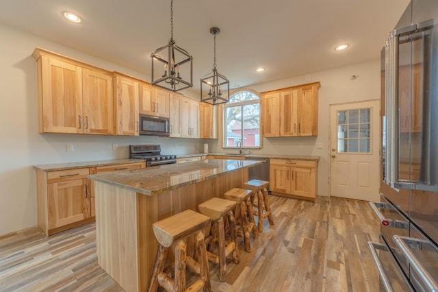 kitchen featuring a breakfast bar area, light brown cabinets, a kitchen island, and stainless steel appliances