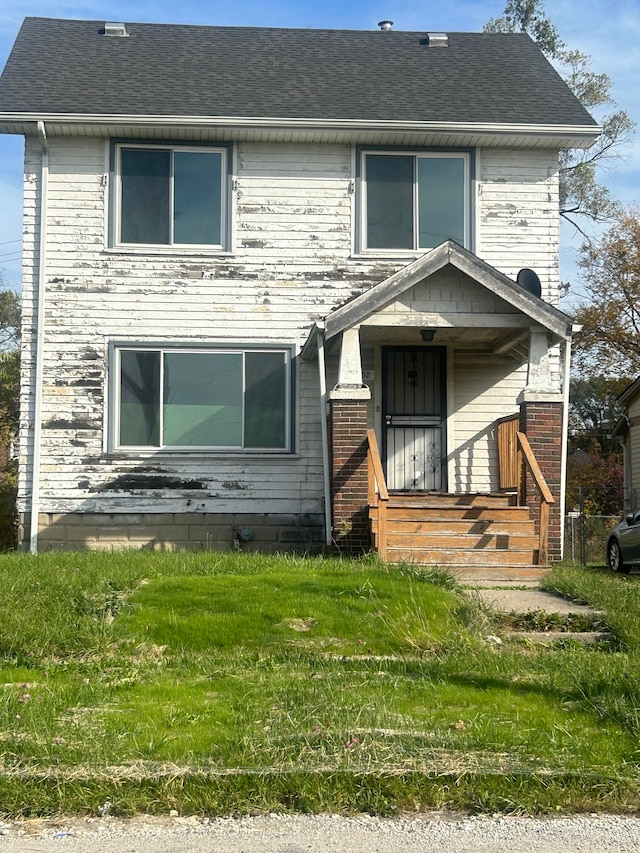 view of front facade featuring a shingled roof and a front yard