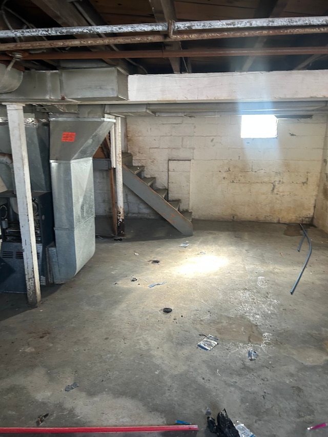 unfinished below grade area featuring heating unit and stairs