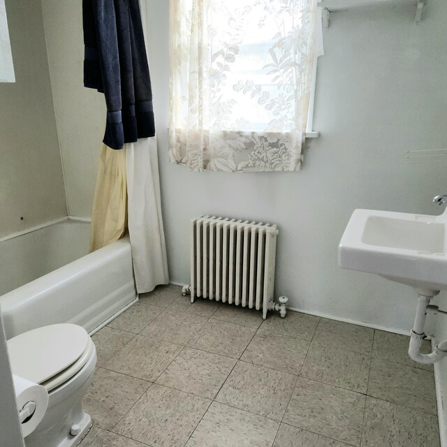 bathroom with shower / bath combination with curtain, toilet, and radiator