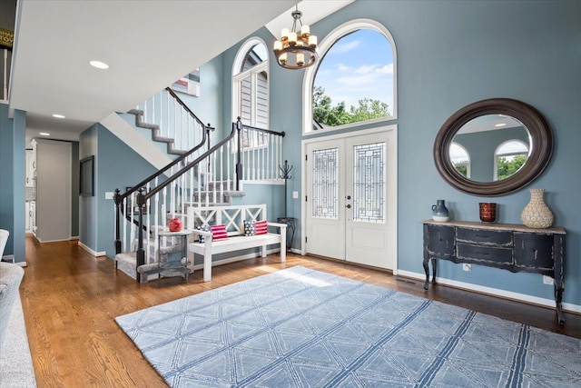 entrance foyer with a notable chandelier, french doors, a high ceiling, and hardwood / wood-style flooring