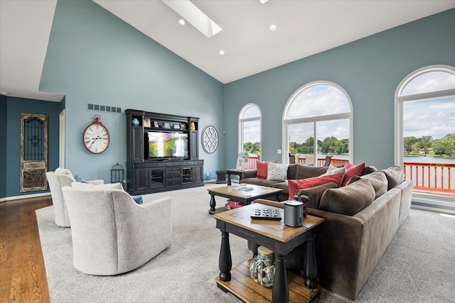 living room featuring wood-type flooring, high vaulted ceiling, and a skylight