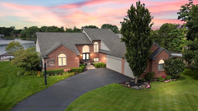 view of front of house with a lawn, a water view, and a garage