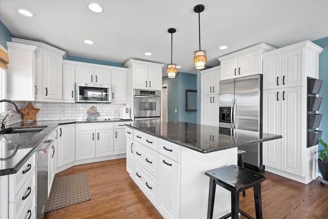 kitchen with sink, a center island, dark wood-type flooring, and appliances with stainless steel finishes