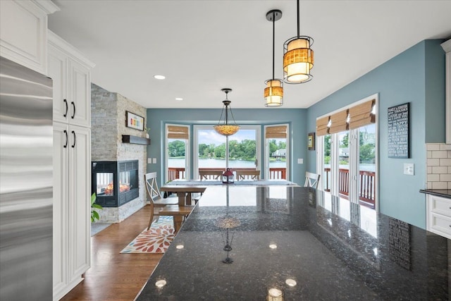 kitchen featuring high quality fridge, white cabinetry, and dark stone countertops