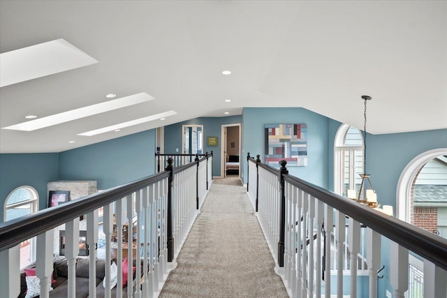 corridor with light carpet, lofted ceiling with skylight, and a wealth of natural light