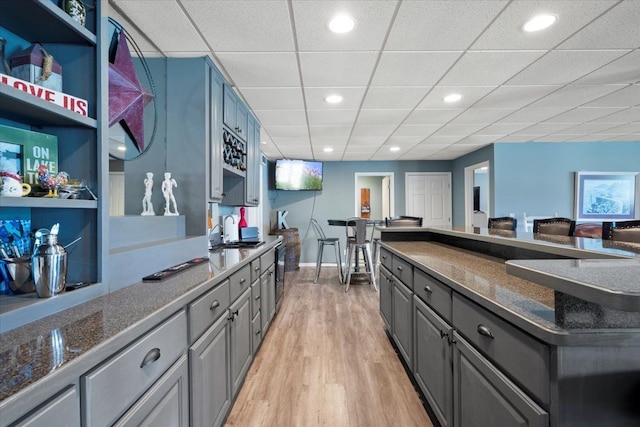 kitchen with gray cabinets, light hardwood / wood-style flooring, a drop ceiling, and sink