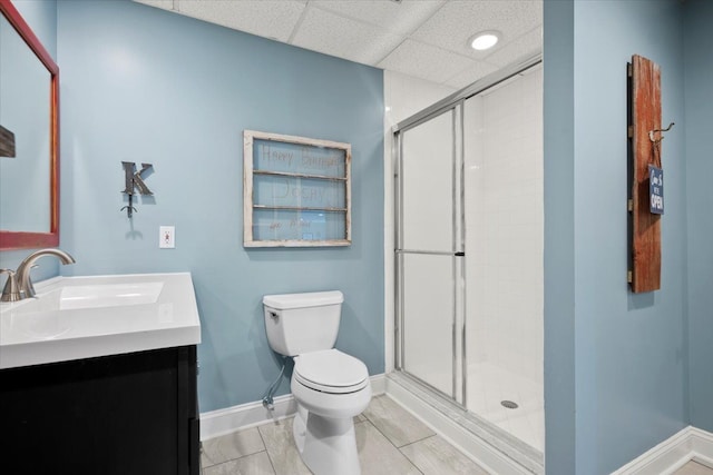 bathroom with a paneled ceiling, vanity, toilet, and a shower with shower door