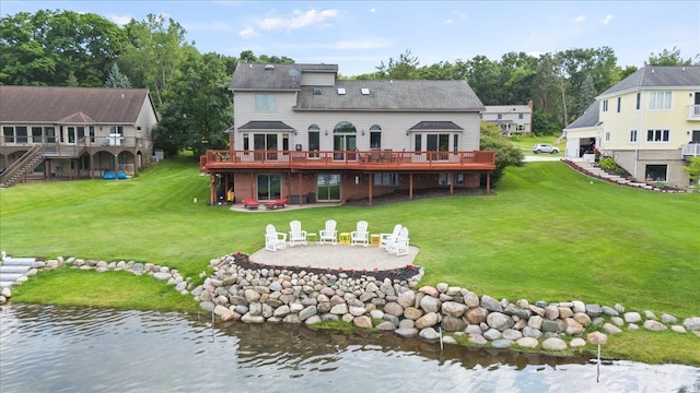 rear view of house featuring a yard, a deck with water view, a patio, and an outdoor fire pit