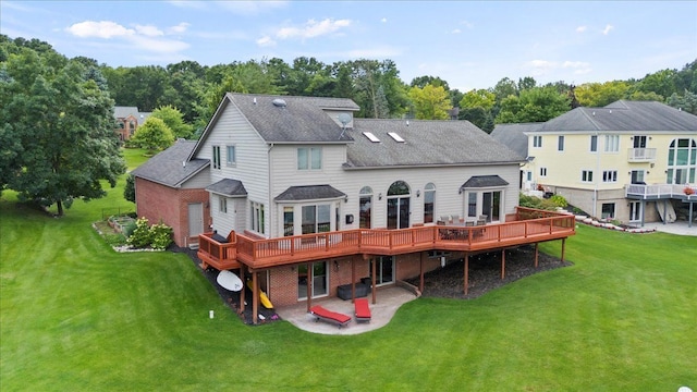 back of house with a wooden deck, a patio area, and a lawn