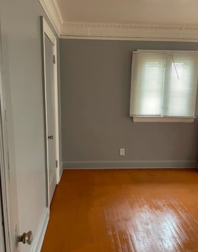 unfurnished room featuring hardwood / wood-style floors and ornamental molding