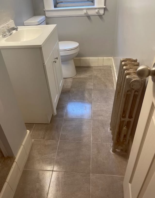 bathroom with radiator heating unit, vanity, toilet, and tile patterned floors