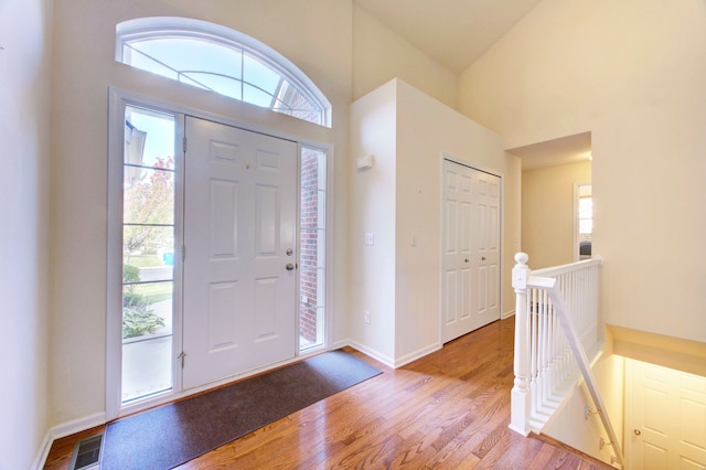 entryway with high vaulted ceiling and light hardwood / wood-style flooring