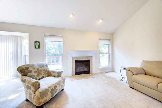 carpeted living room featuring a tile fireplace and lofted ceiling