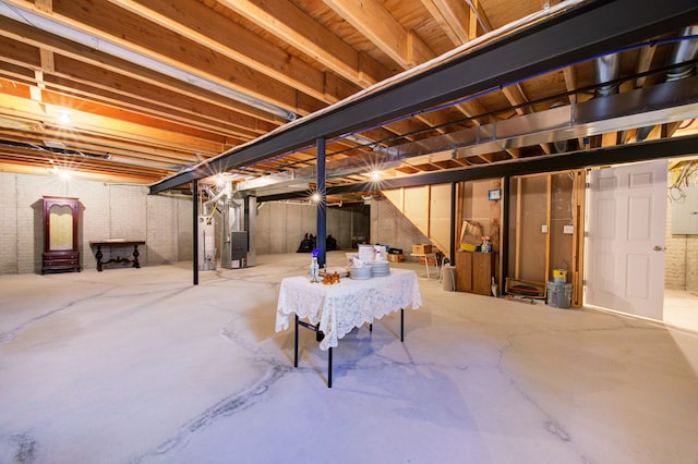 basement with heating unit, water heater, and brick wall