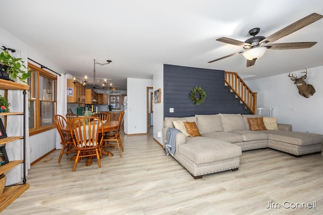 living room with ceiling fan with notable chandelier and light hardwood / wood-style floors