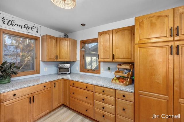 kitchen featuring light hardwood / wood-style floors, light stone counters, and decorative light fixtures