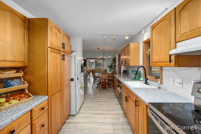 kitchen with sink, an inviting chandelier, light hardwood / wood-style flooring, stainless steel appliances, and light stone countertops