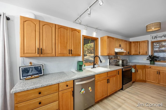 kitchen with sink, light hardwood / wood-style flooring, light stone countertops, and appliances with stainless steel finishes