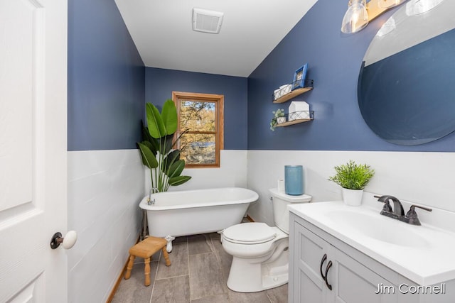 bathroom with a washtub, vanity, and toilet