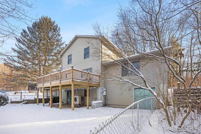 snow covered back of property with ac unit and a deck