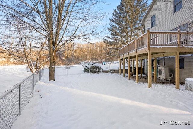 snowy yard featuring a wooden deck and ac unit