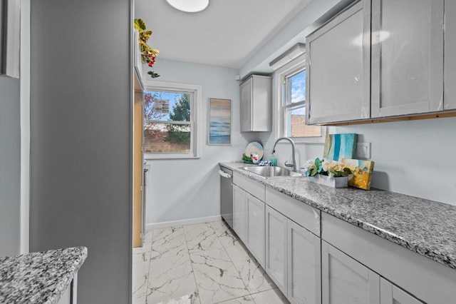 kitchen with gray cabinetry, dishwasher, light stone counters, and sink