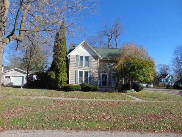 traditional-style home with a garage, a front lawn, and an outbuilding