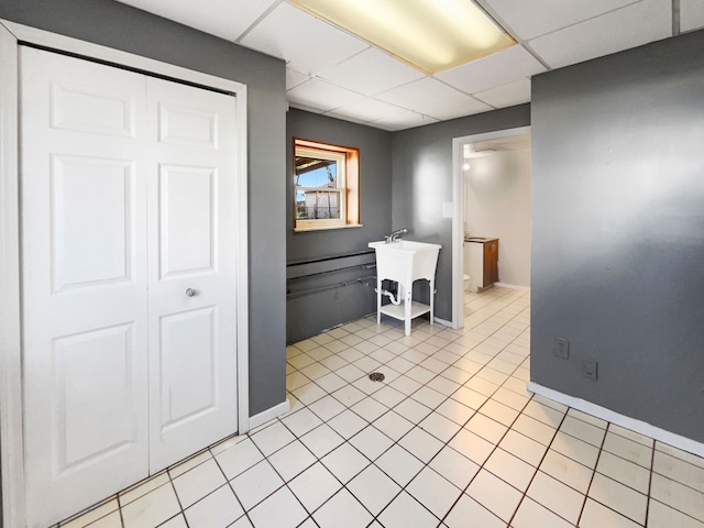 kitchen with a drop ceiling, light tile patterned floors, and sink