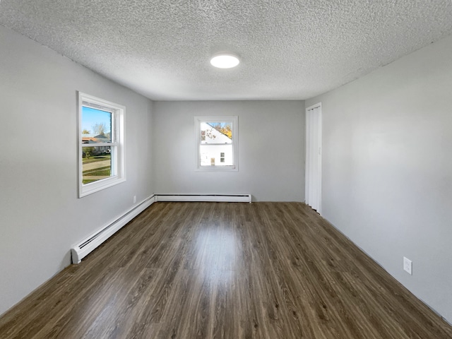 empty room featuring baseboard heating, dark wood-type flooring, and a textured ceiling