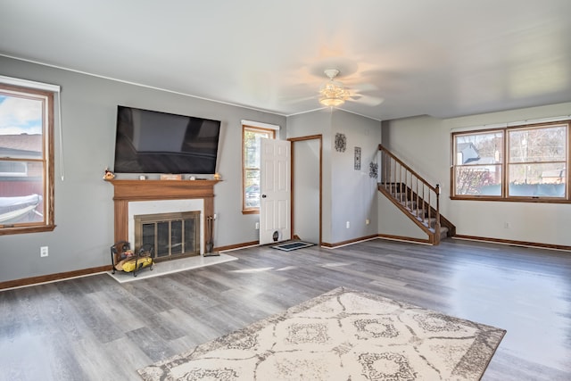 unfurnished living room featuring ceiling fan, plenty of natural light, and wood-type flooring