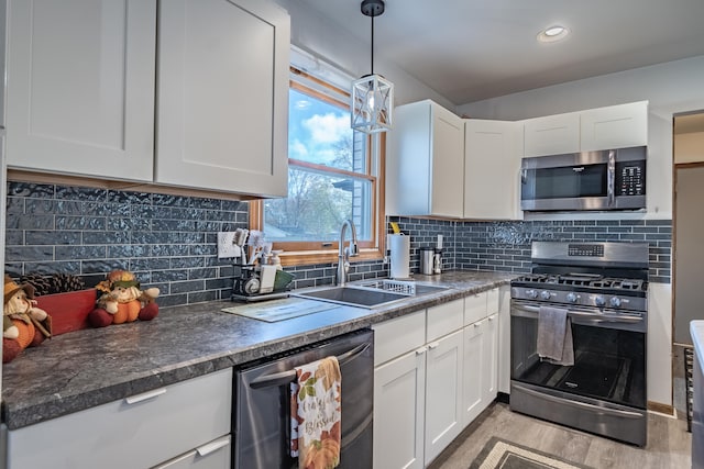 kitchen with decorative backsplash, white cabinetry, sink, and appliances with stainless steel finishes