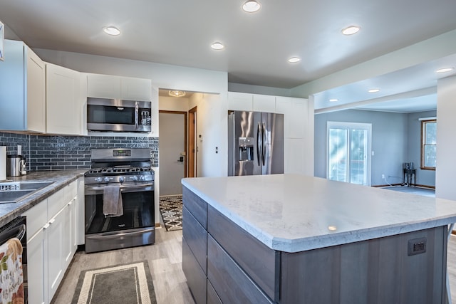 kitchen with light hardwood / wood-style flooring, white cabinets, stainless steel appliances, and a kitchen island