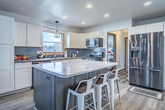 kitchen featuring white cabinets, appliances with stainless steel finishes, and decorative light fixtures