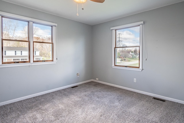 empty room with a wealth of natural light, carpet, and ceiling fan