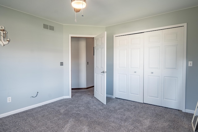 unfurnished bedroom featuring ceiling fan, a closet, and dark colored carpet