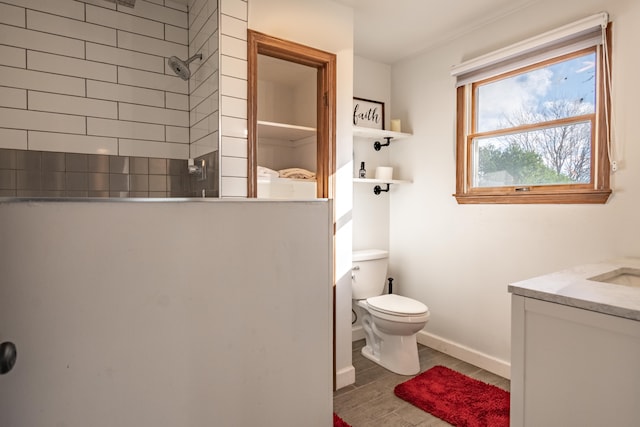 bathroom with tiled shower, vanity, and toilet