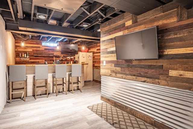 bar featuring hardwood / wood-style floors, white fridge, and wooden walls